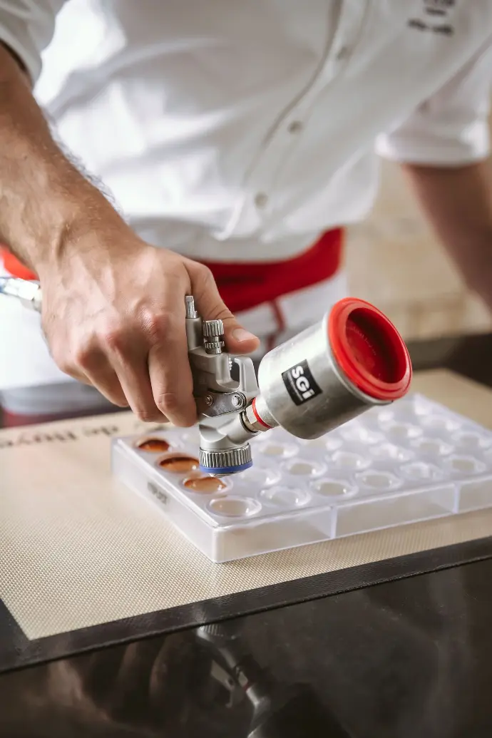 SATAminijet 4400 B avec godet aluminium en action – pulvérisation de chocolat Pulvérisation de chocolat avec un pistolet SATAminijet 4400 B équipé d’un godet en aluminium