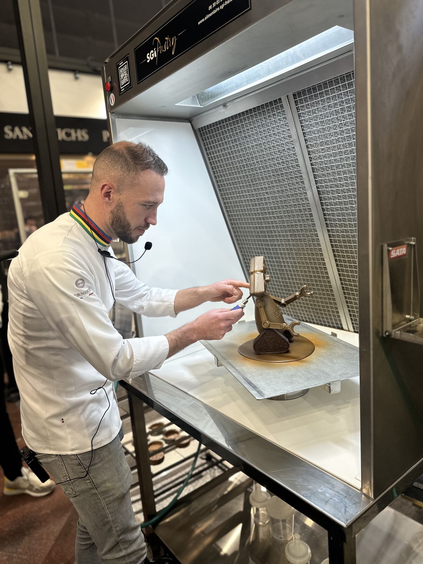 Finitions pâtissières en hotte SGI Pastry lors du SIRHA 2025 Pâtissier peaufinant sa création dans une hotte SGI Pastry au SIRHA 2025